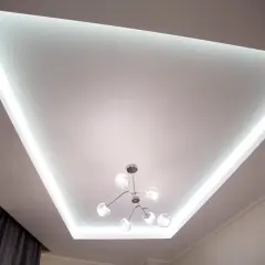 Nowoczesny sufit napinany z podświetleniem LED tworzy niepowtarzalne inspiracje dla wnętrz. Stylowa lampa dodaje elegancji.