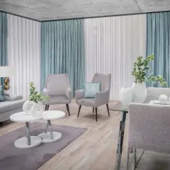 Eleganckie firany w salonie tworzą przytulną atmosferę. Szare fotele i kanapa dopełniają nowoczesny wystrój.