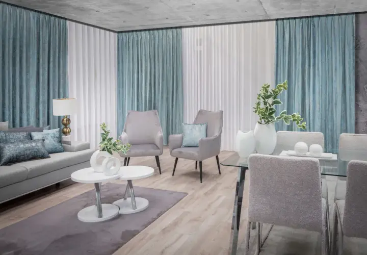 Eleganckie firany w salonie tworzą przytulną atmosferę. Szare fotele i kanapa dopełniają nowoczesny wystrój.