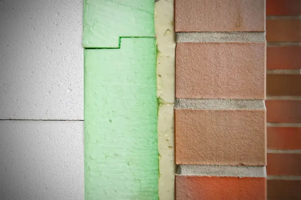 Warstwowa izolacja fundamentów: biały styropian, zielony styrodur i cegła. Jaki styrodur na fundamenty? Ten zielony wygląda solidnie.