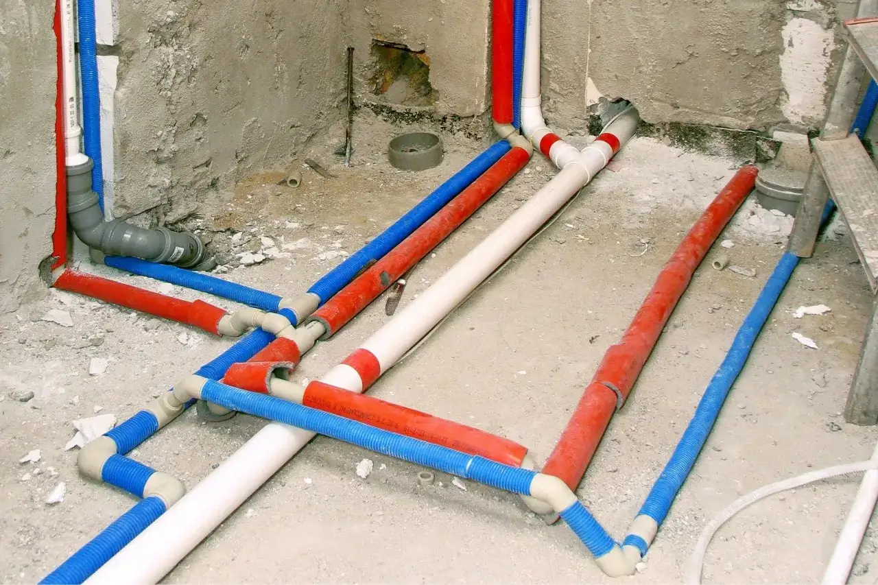 Sieć rur wodnych i kanalizacyjnych w trakcie budowy, widoczna hydraulika przed tynkami.