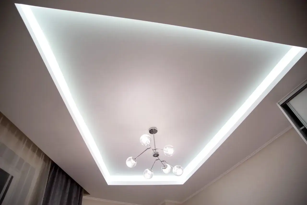 Nowoczesny sufit napinany z podświetleniem LED tworzy niepowtarzalne inspiracje dla wnętrz. Stylowa lampa dodaje elegancji.